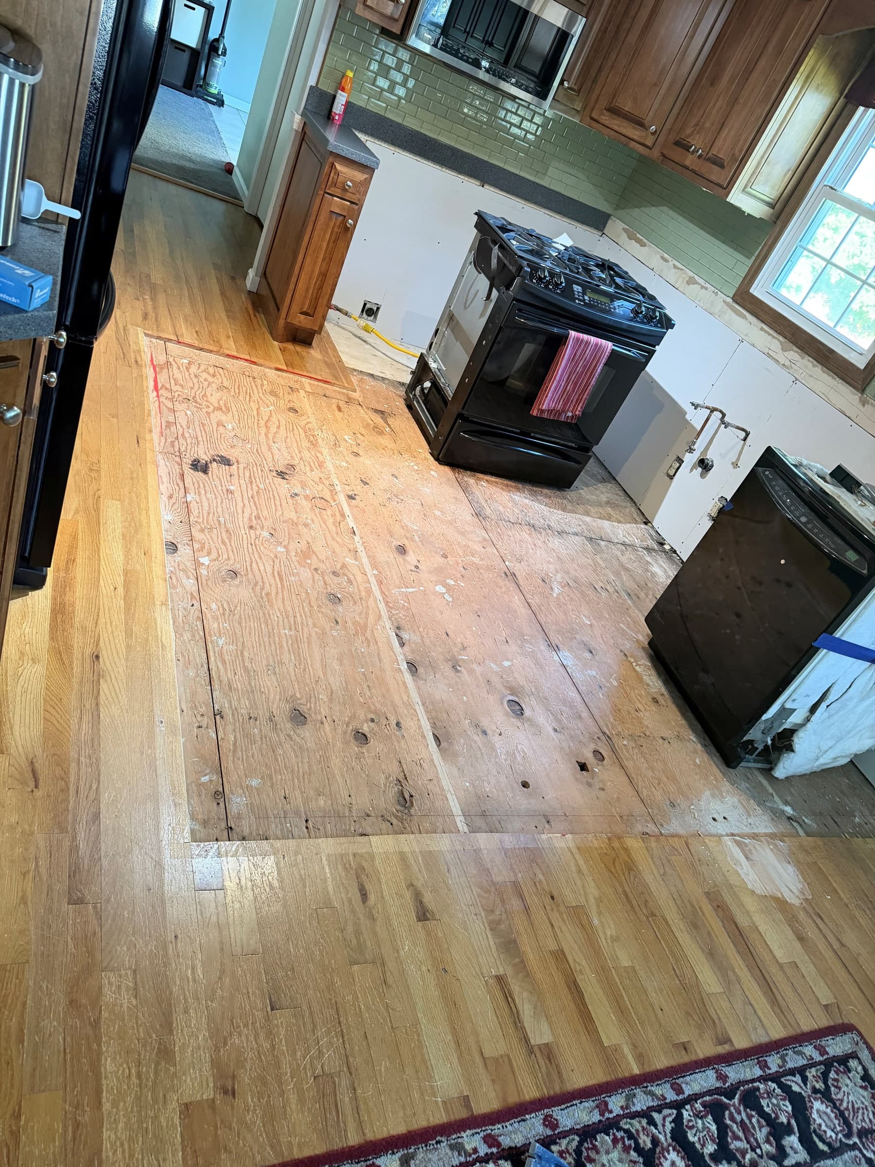 Exposed plywood in an Ellington kitchen repair area surrounded by existing hardwood flooring