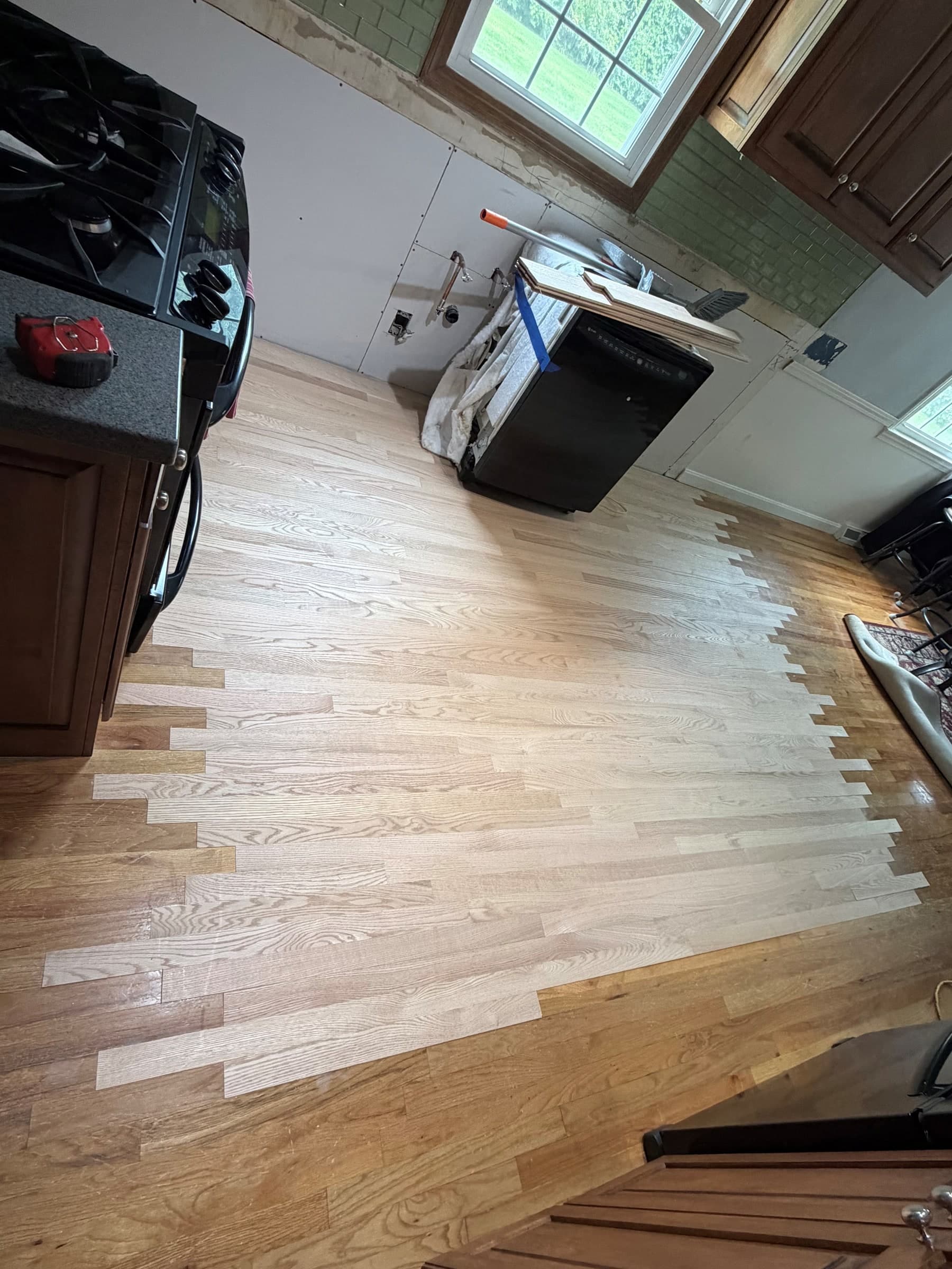 Alternate view of staggered board ends joining new unfinished red oak to existing Ellington kitchen hardwood