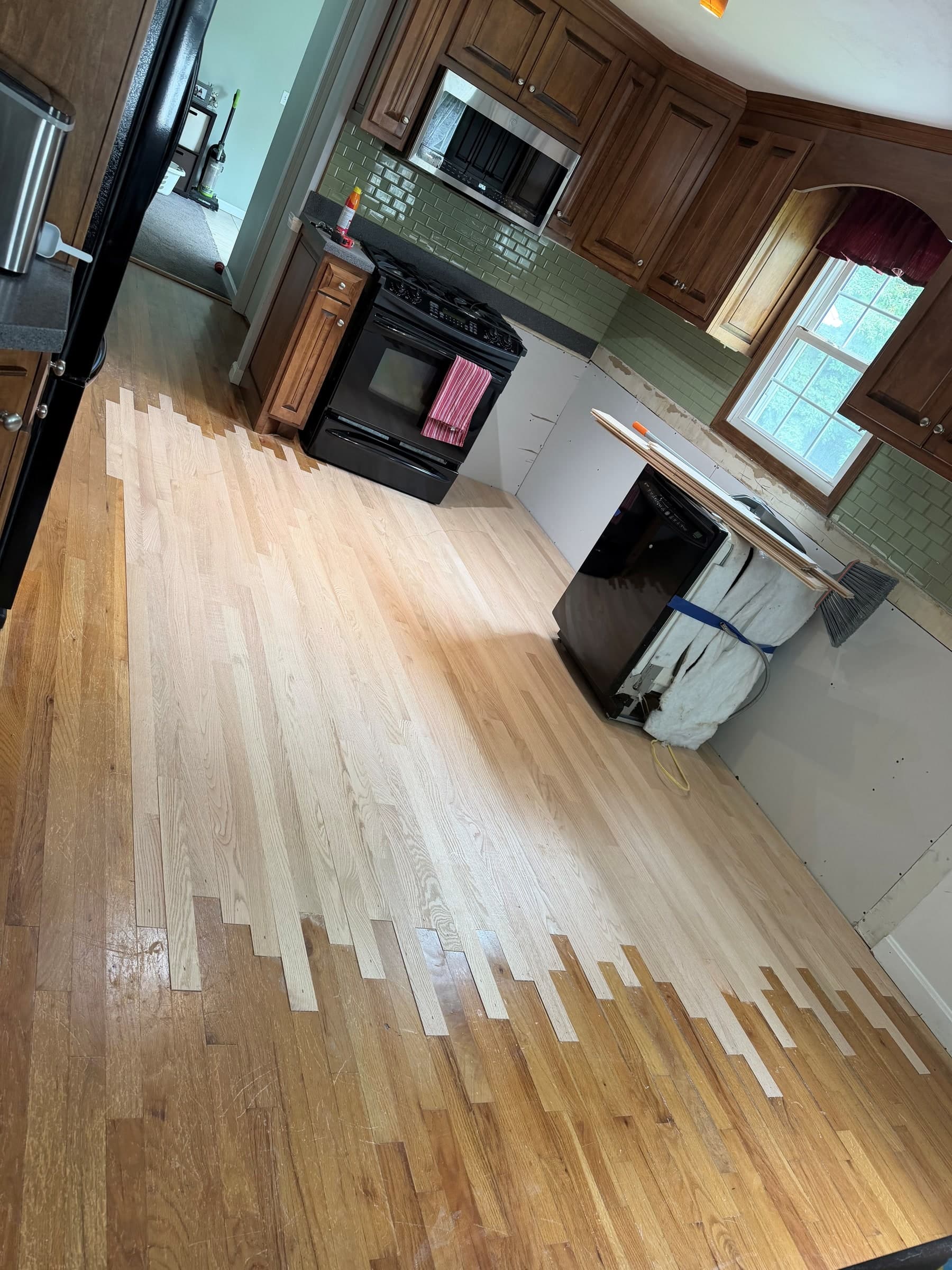 New unfinished red oak boards woven into the existing hardwood around an Ellington kitchen repair