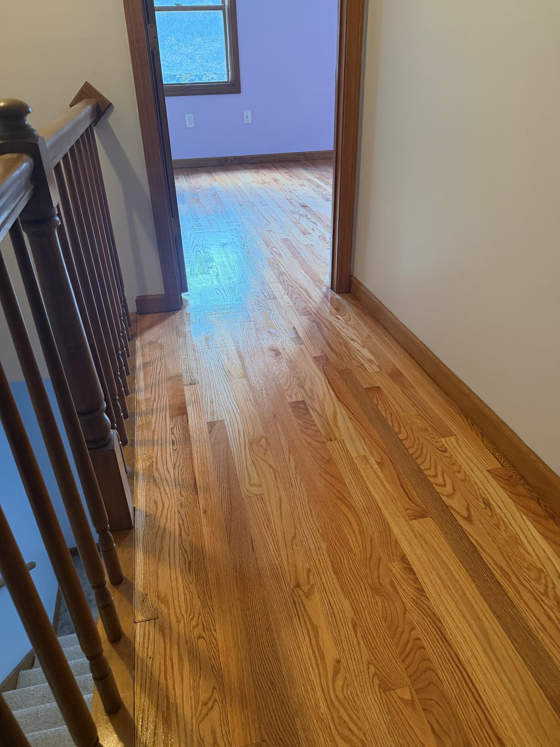 Refinished Enfield hallway hardwood beside a wood railing and leading into a bedroom