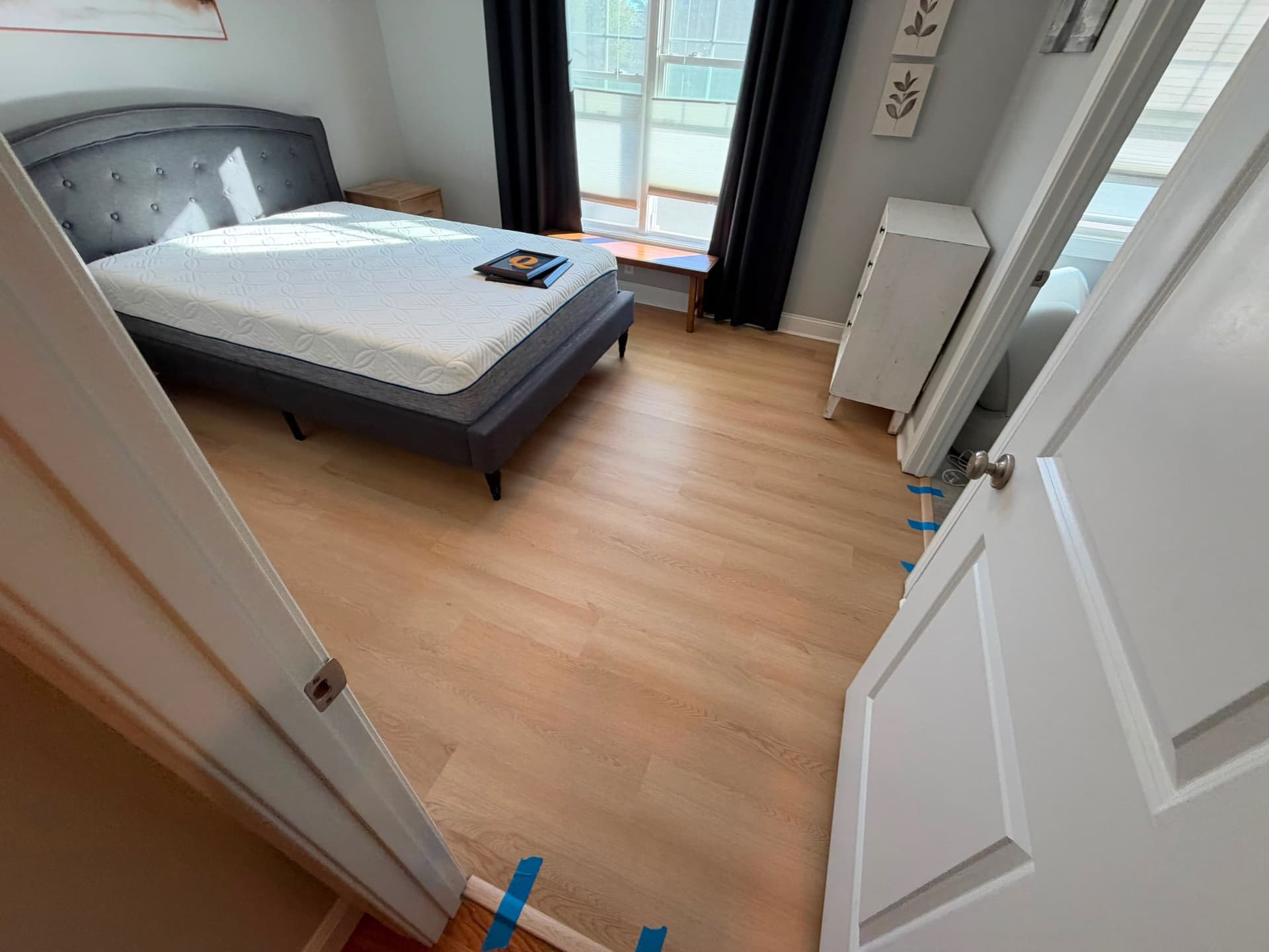 White Sand LVP at a Newington bedroom doorway with temporary blue painter's tape visible at the threshold