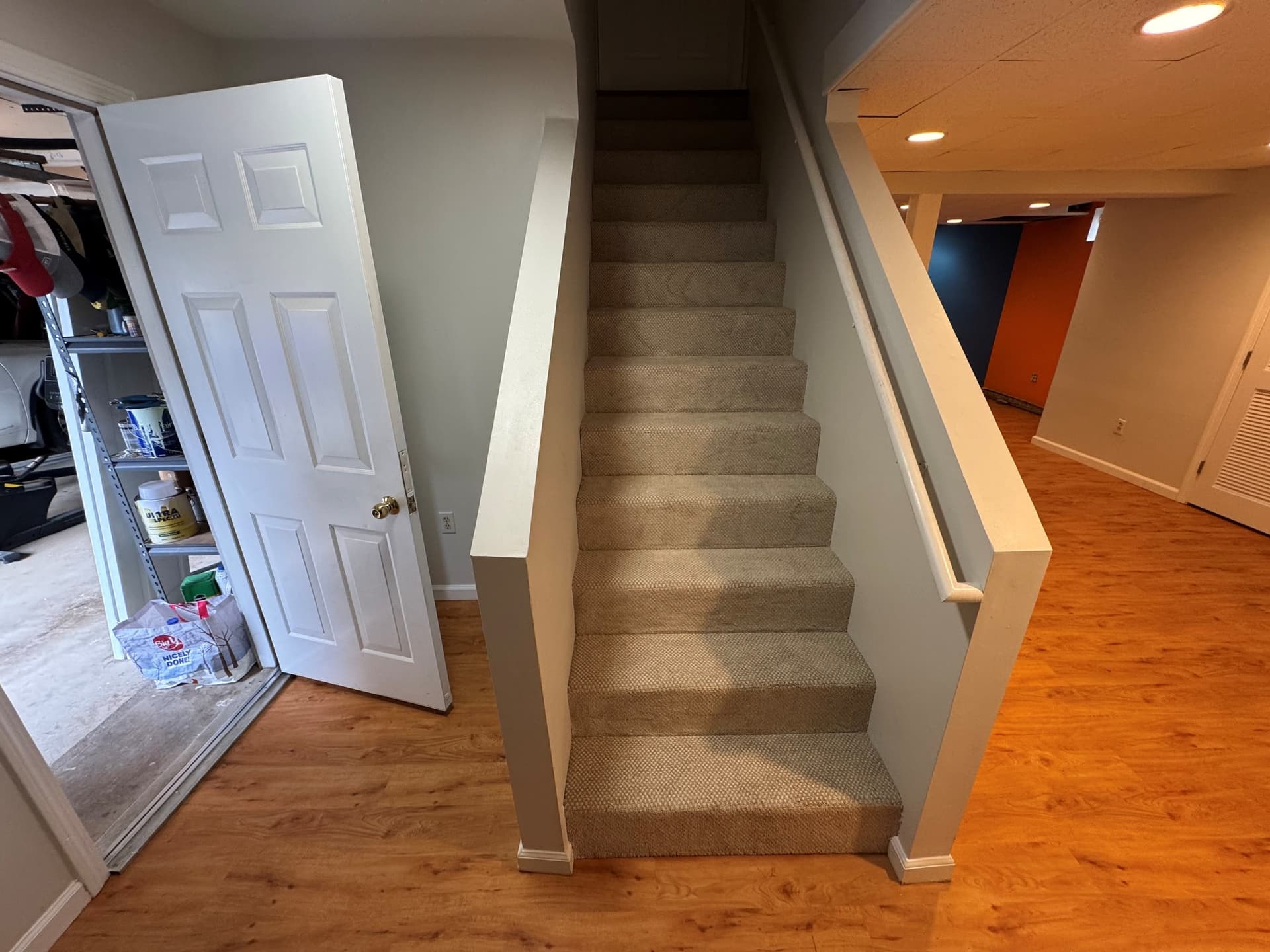 Basement stairs fully carpeted in Dixie Home Finery Nectar beside the new Light Cherry vinyl flooring in a Rocky Hill home