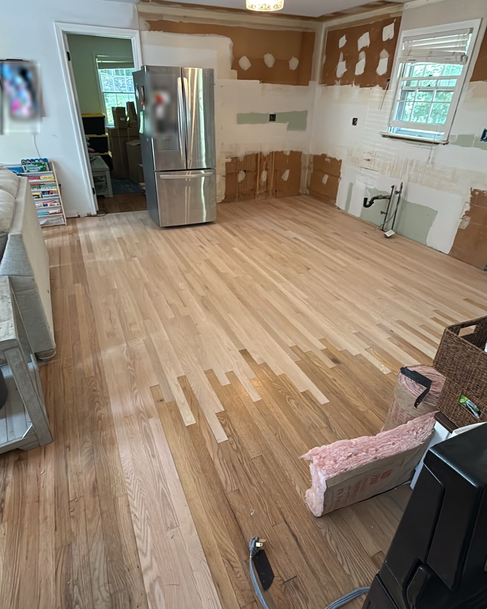 Unfinished select red oak boards woven into existing hardwood between a Simsbury kitchen and dining room before sanding and refinishing
