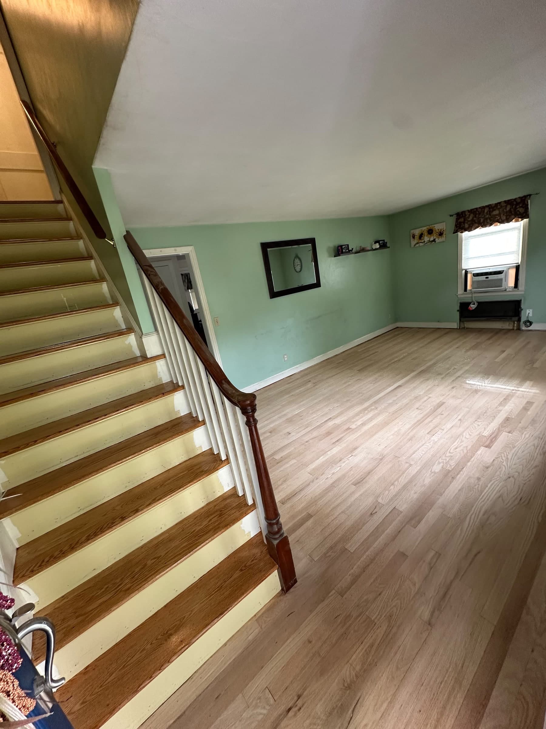 Sanded hardwood living-room floor beside the staircase in a Berlin home, before finishing