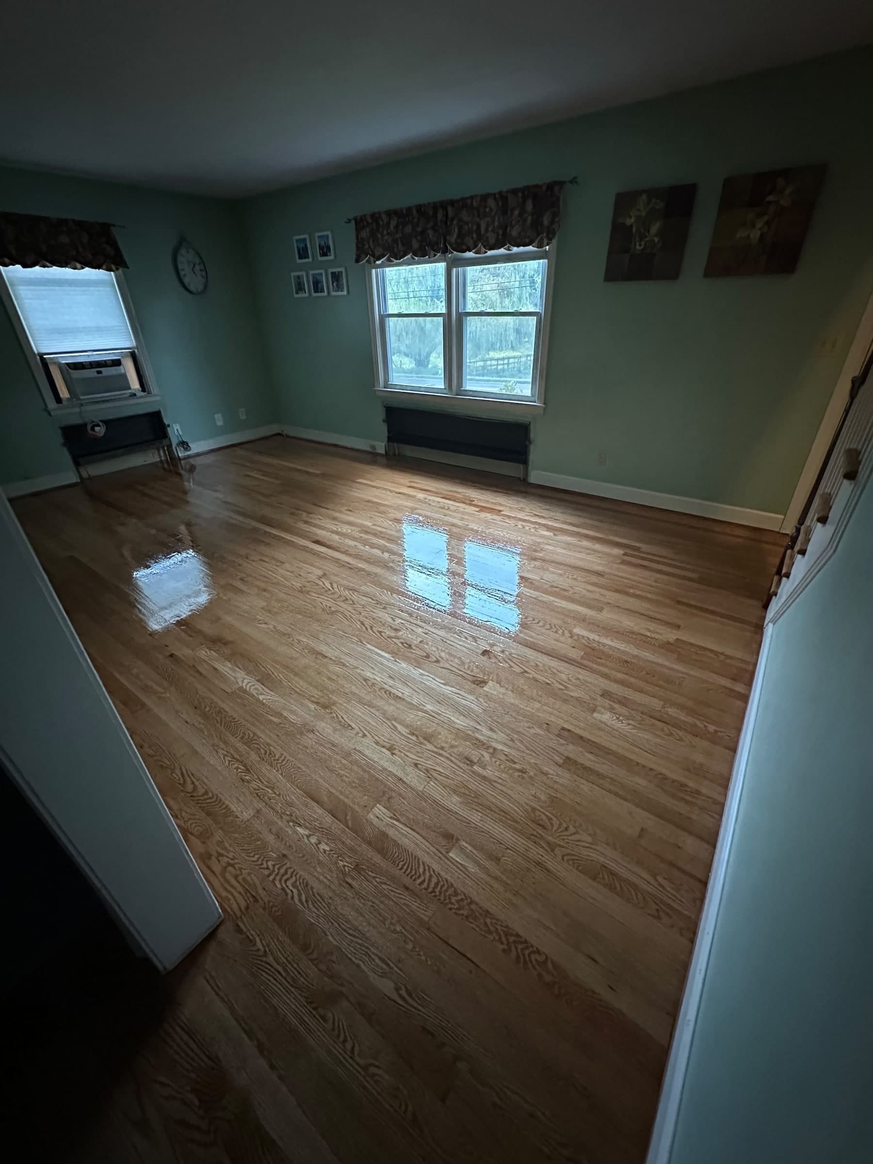 Refinished hardwood living-room floor with window reflections in a Berlin home