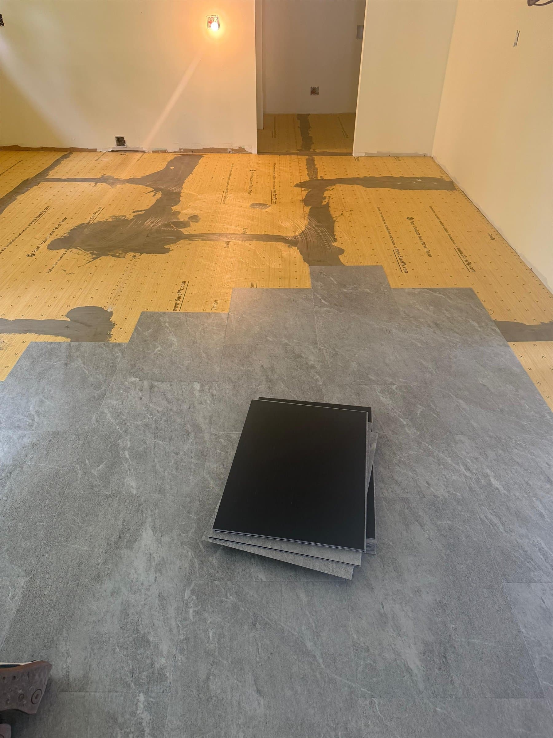 Sterling Quartzite LVT installation progressing across prepared plywood underlayment in a Kensington kitchen