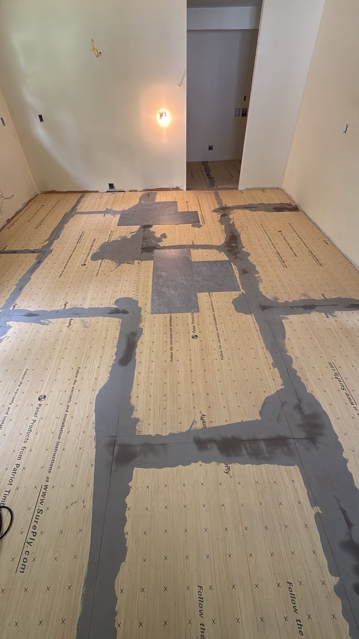 Prepared plywood underlayment and treated seams before gluedown LVT installation in a Kensington kitchen
