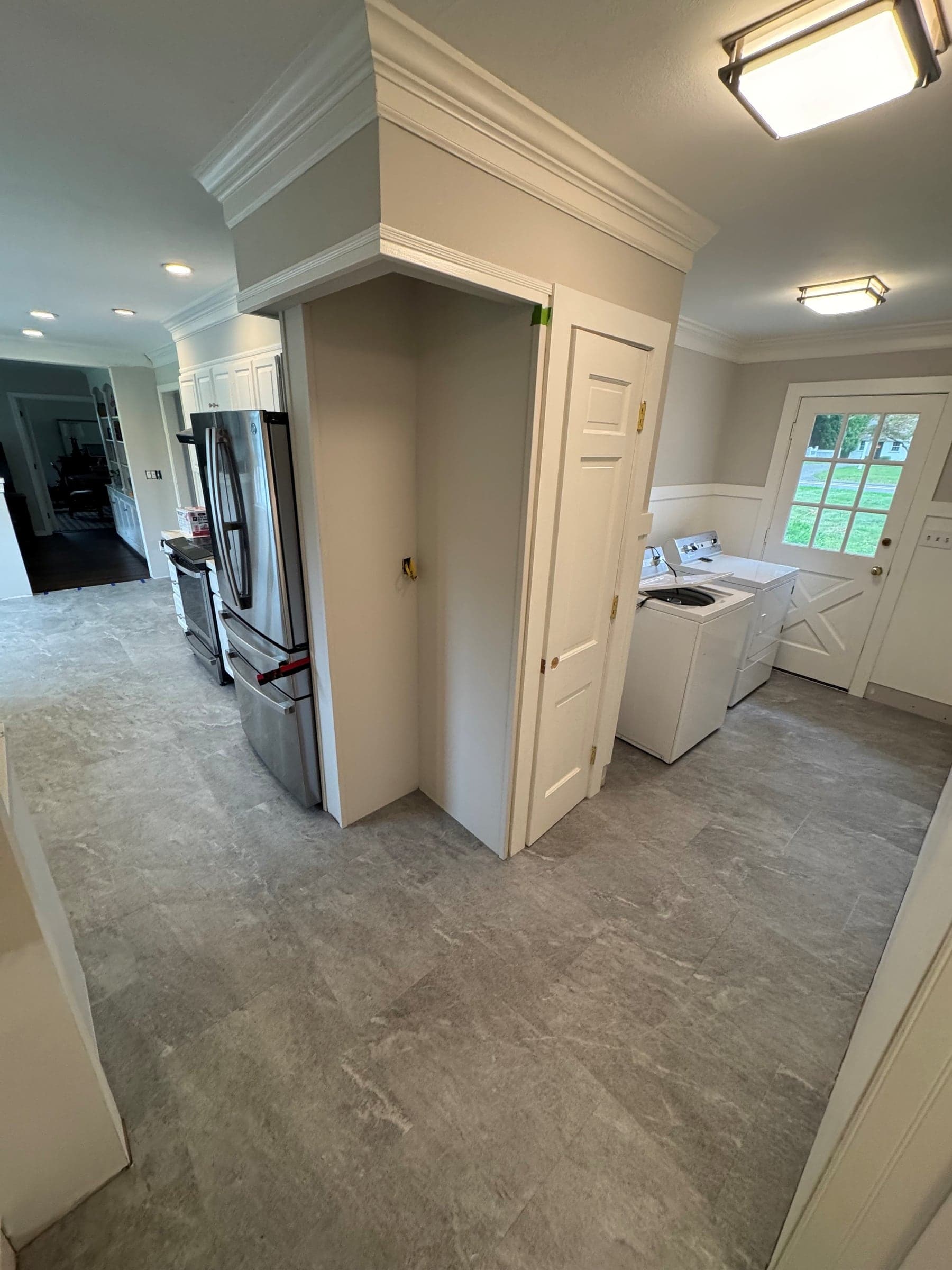 Karndean Sterling Quartzite stone-look flooring connecting a Kensington kitchen with stainless steel appliances and a laundry area