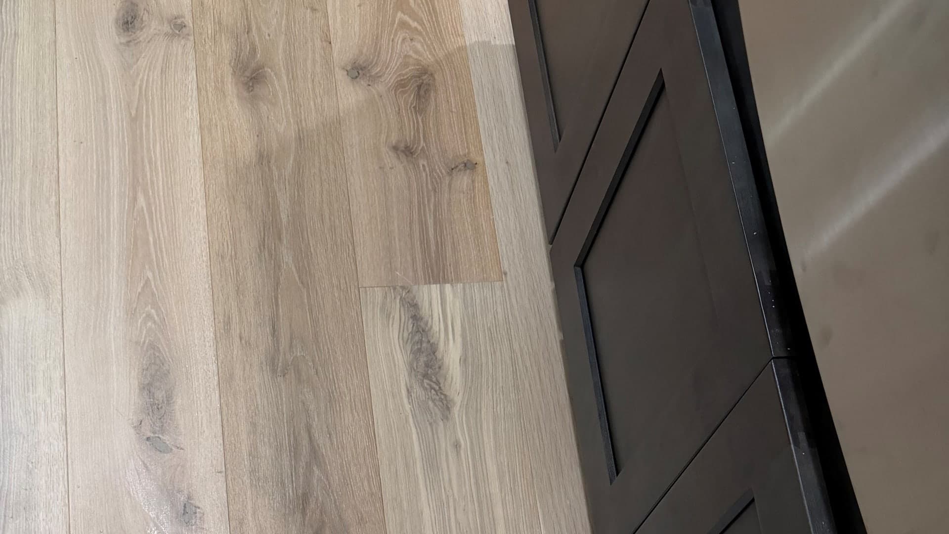 Completed engineered hardwood board replacement beside a kitchen island in Colchester