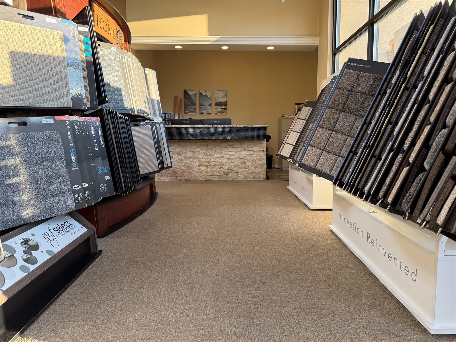 Neutral carpet tile installed along the main aisle between carpet sample displays in the Floors Now Newington showroom