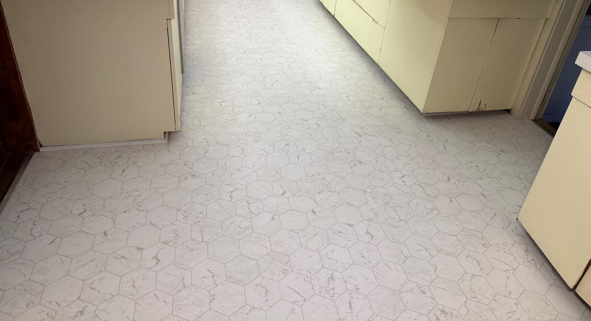 Completed light hexagonal-pattern Tarkett Home Trutext Nero Hex sheet vinyl between pale kitchen cabinets in a Salisbury home