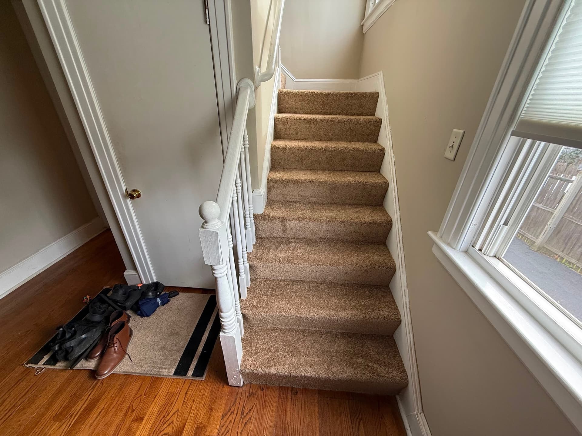 Warm tan NRF carpet fitted across the main staircase beside a white railing and tall windows